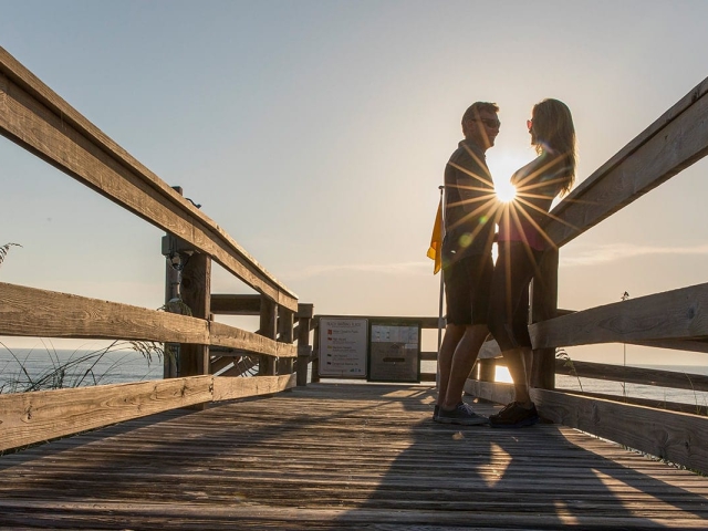 A couple standing on the boardwalk at Orchid Island at sunrise