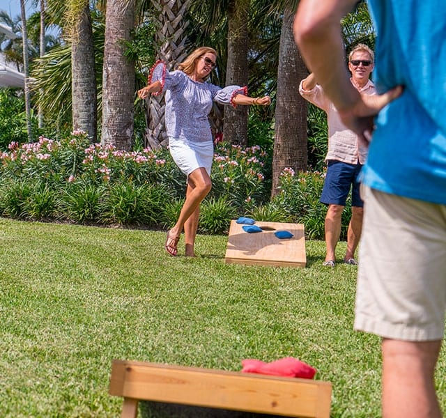 A group of friends play corn hole on the lawn at Orchid Island.