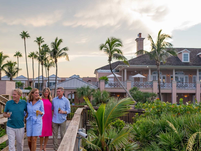 2 couples walking from Orchid Island's beach club over the boardwalk towards the ocean.
