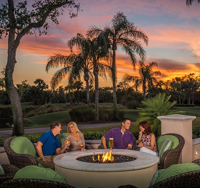 Two couples sit around one of the Fire Pits at Orchid Island's Golf Club at sunset