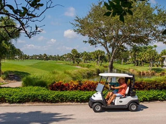 Couple riding in a Golf Cart at Orchid Island Golf &amp; Beach Club