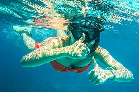 Woman underwater snorkeling, giving a thumbs up to the camera in Vero Beach, FL