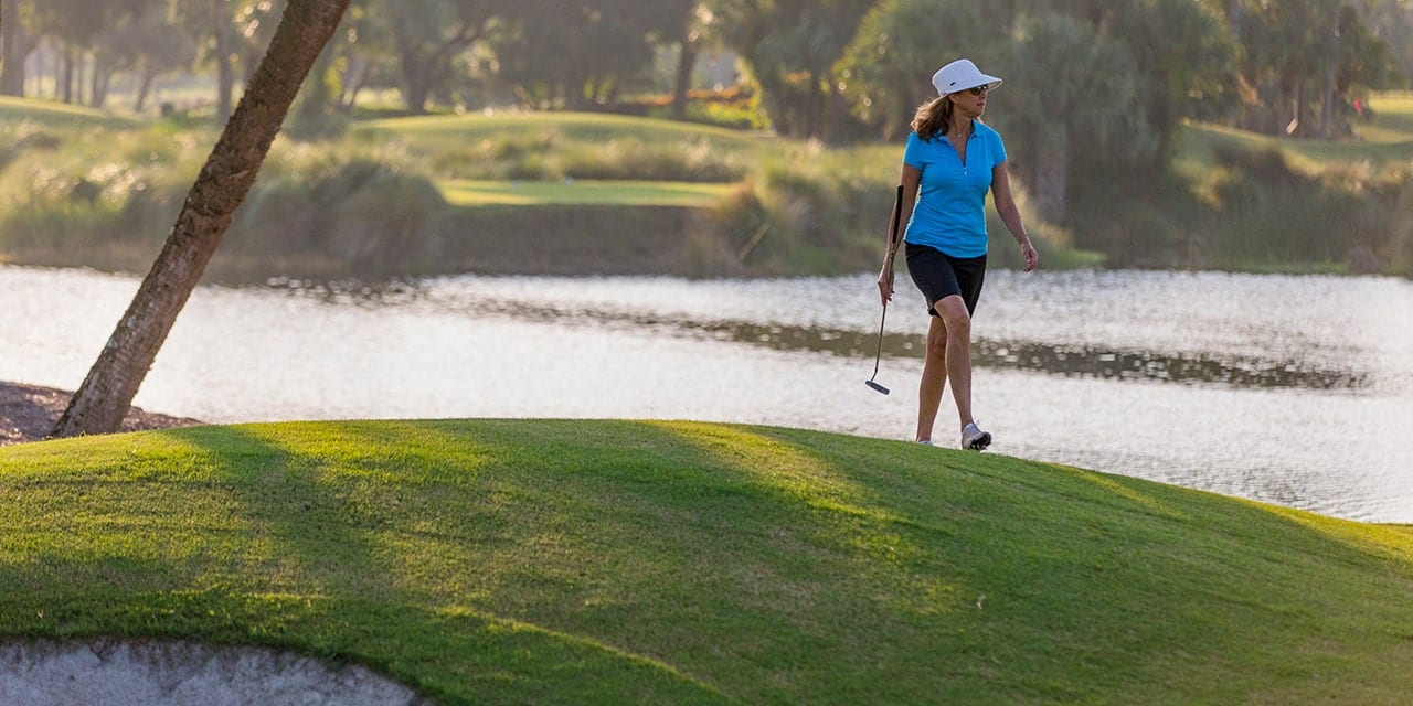 Woman Golfer walking along the Orchid Island Golf Course carrying a putter.