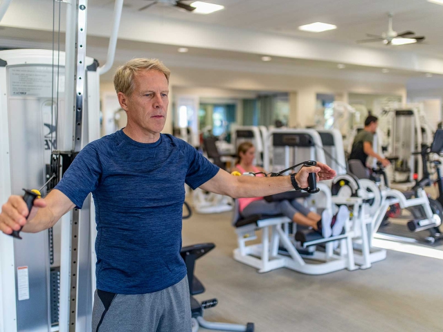 Man training on one of the exercise machines in the Orchid Island Fitness Club