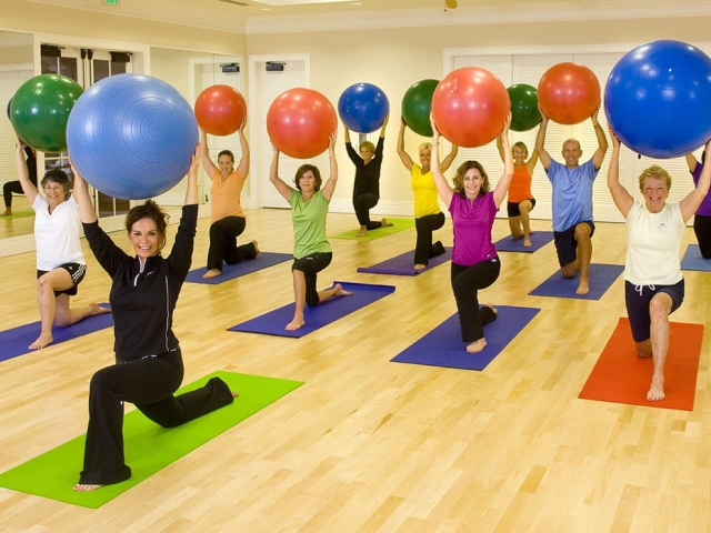 Coed group of people excising with yoga balls in Orchid island Fitness Class