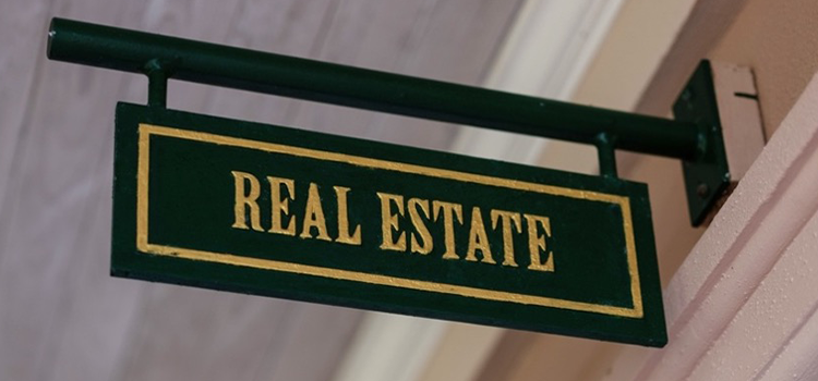 Green real estate sign hanging from a metal bracket
