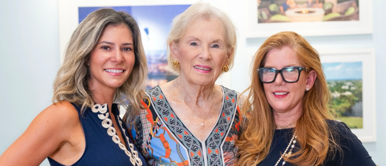 Three women posing together at indoor art gallery
