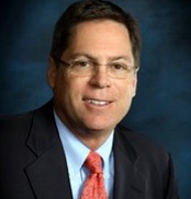 Rob Tench in suit and glasses against dark backdrop