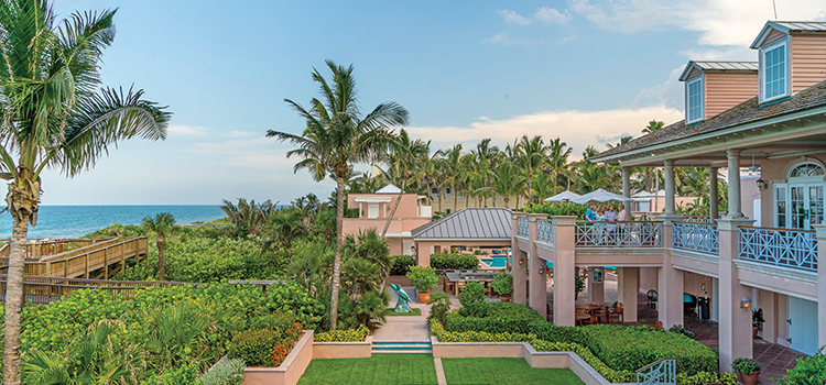 Clubhouse gardens with palm trees and ocean visible in the distance.