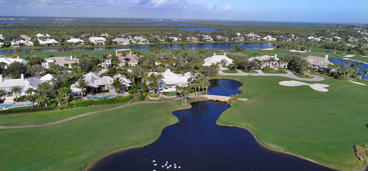 Aerial view of golf course fairways, water features, and nearby homes.