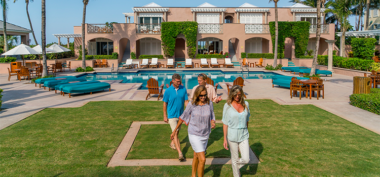 Resort courtyard with swimming pool, lounge chairs, palm trees, and buildings.