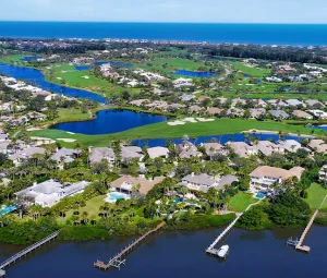 Aerial view of river waterways leading to the ocean with homes and greenery.