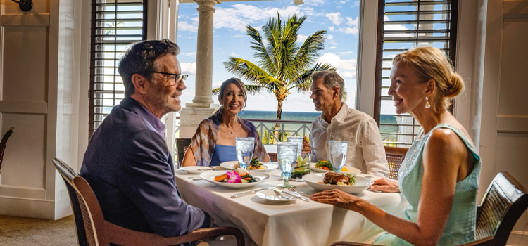 Group dining indoors with ocean view through open doors