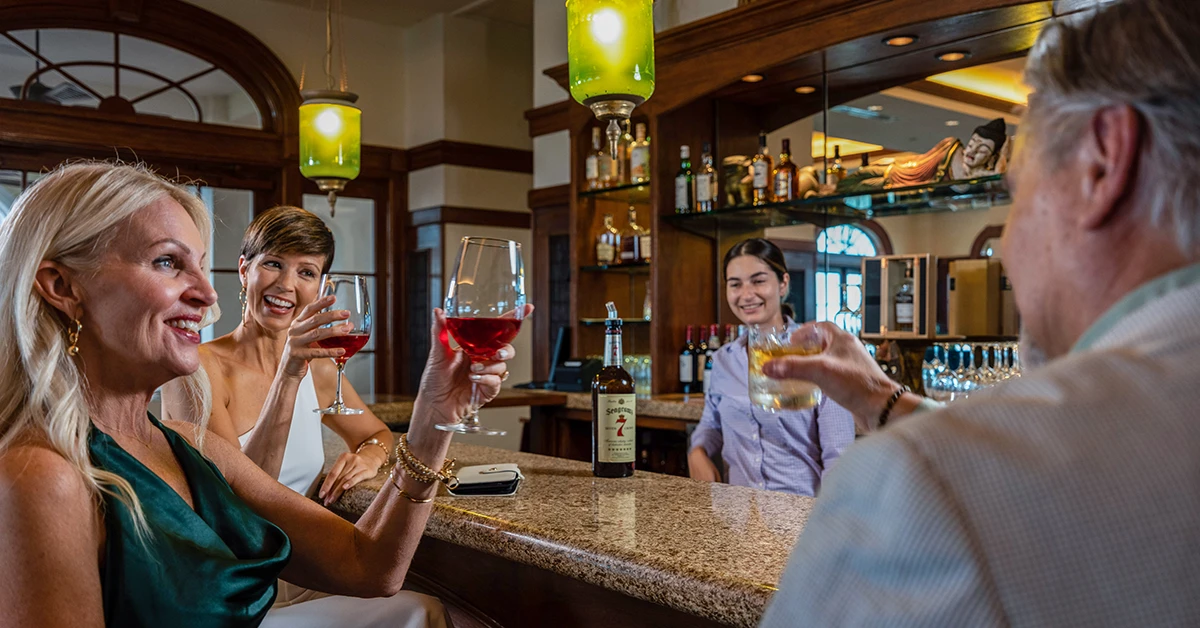 Adults toast with drinks at an upscale private club bar.
