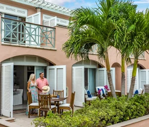Couple standing on a tropical villa patio with palm trees.