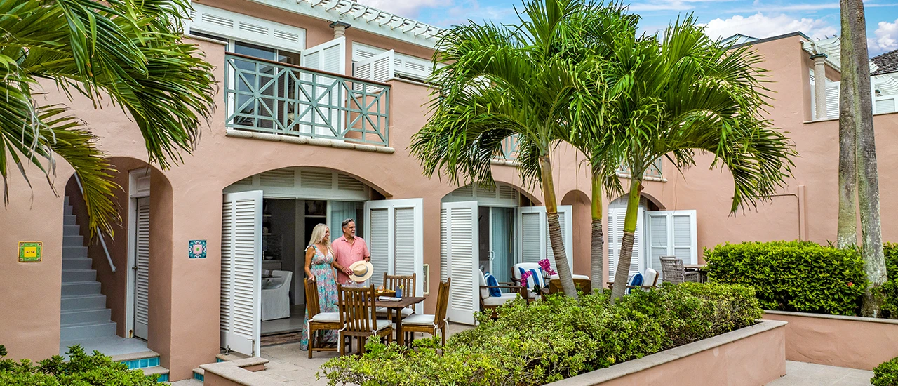 Couple standing on a tropical villa patio with palm trees.
