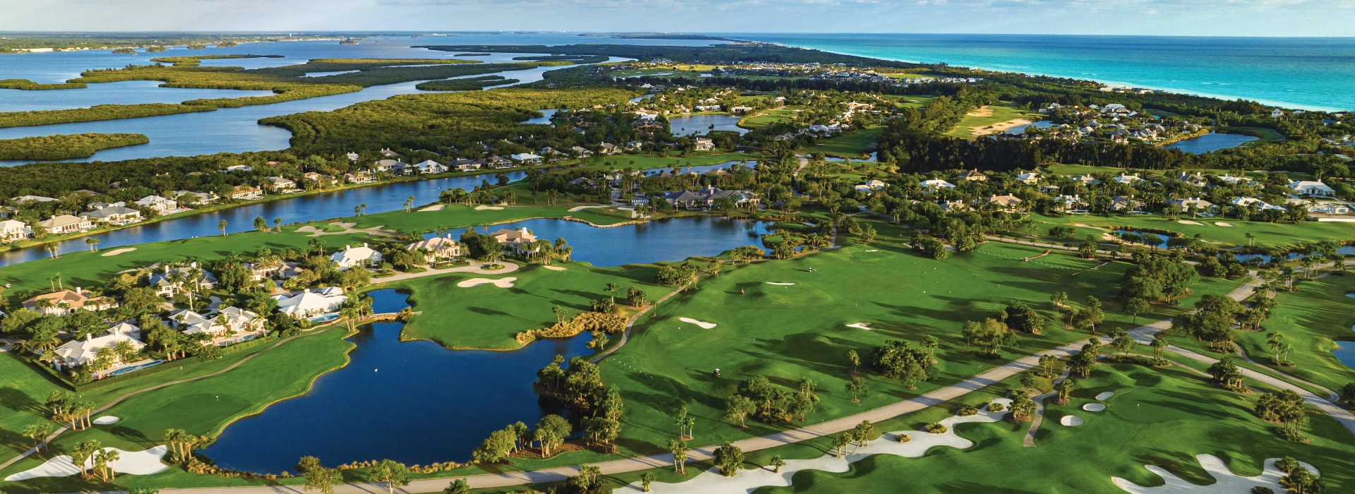 Aerial view of Orchid Island Golf & Beach Club featuring lush golf fairways, lakes, luxury homes, and the Atlantic Ocean.